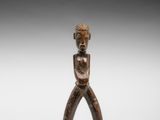 une petite figurine en bois représentant un homme tenant un couteau