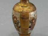 a gold vase with a picture on it sitting on a table