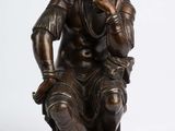 bronze statue of a man sitting on a stool with a dog