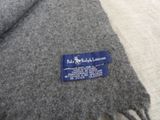grey wool blanket with a blue label on it sitting on a bed