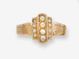 un gros plan d'une bague en or ornée de perles sur fond blanc