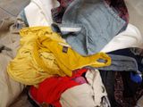 a pile of clothes sitting on a bed next to a pillow
