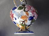 a vase with a floral design on it hanging on a wall