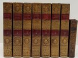 six vieux livres sont alignés sur une surface blanche