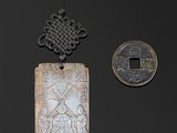 deux pendentifs chinois en argent et une pièce de monnaie sur un fond noir