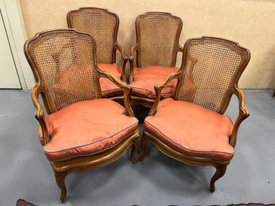 quatre chaises anciennes à dossier en rotin, avec des coussins orange
