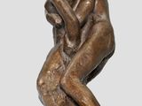 bronze statue of a man sitting on a rock with his hands on his face