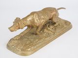 statue en bronze représentant un chien, posée sur un plateau, sur une surface blanche