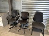 two office chairs sitting next to each other in front of a garage door