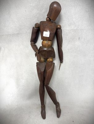 un mannequin en bois posé sur une surface blanche