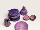 un ensemble de plats et de bols violets posés sur un plan de travail blanc