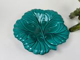 a green plate with a flower on it next to a green plant