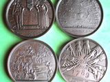 four commemorative coins of different sizes and shapes on a green surface