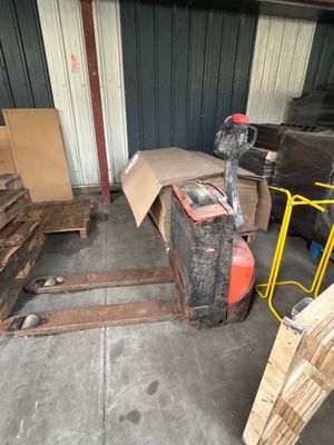 Plusieurs palettes de bois sont entreposées dans une zone de stockage, à côté d'autres palettes de bois.