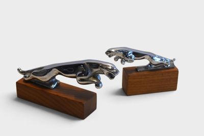 pair of silver jaguars on wooden bases on a white background