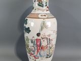a white vase with a painting on it sitting on a table