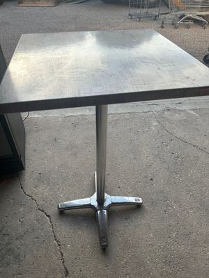 une table avec un plateau carré et un piètement en métal
