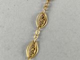 a gold plated necklace with a long chain that has a leaf design on it
