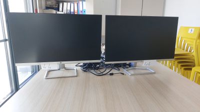deux écrans d'ordinateur posés sur un bureau en bois