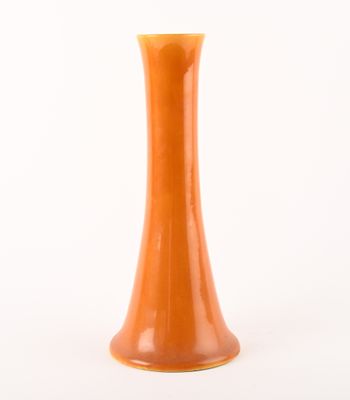 an orange vase on a white surface with a white background