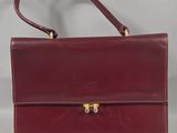 a red leather handbag with a gold clasp