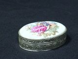 a small silver box with a picture of a woman on it