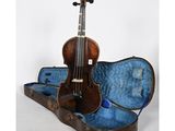 un vieux violon repose dans son étui, posé sur une surface blanche