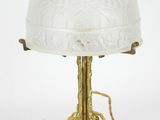 an antique brass table lamp with a glass shade and a spider on the base
