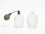 two glass bottles that are next to each other on a white surface