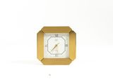a gold clock with a white face on a white background