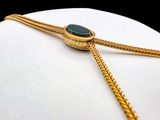 a gold chain with a green stone on it
