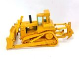 un petit bulldozer jaune posé sur une surface blanche