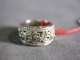 a silver ring with a red ribbon on a gray surface