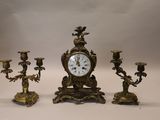 a clock and three candlesticks sitting on a table