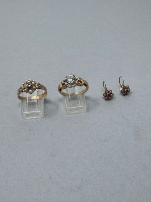 deux bagues en or et une paire de boucles d'oreilles posées sur une table