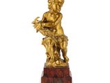 une figurine en or représentant un garçon tenant une fleur, posée sur un socle en marbre