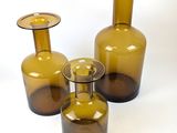 three brown glass vases sitting next to each other on a white surface