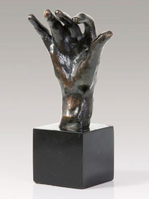 bronze sculpture of a hand holding a ball on a black base