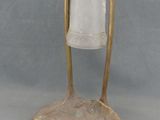 lampe de table en laiton et verre dépoli, posée sur un socle, sur fond gris