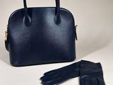 a blue handbag and gloves sitting on top of a table