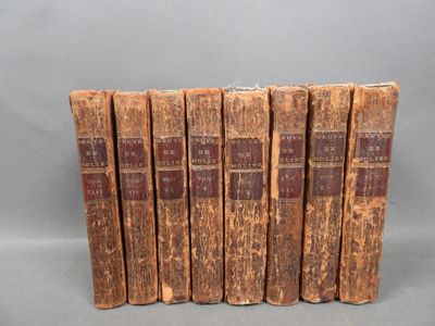 six old books sitting on top of each other on a gray surface
