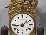 a gold clock that is sitting next to two candles