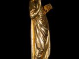 gold statue of a woman holding a book in her right hand