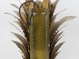 a gold vase with scissors in it on a white surface