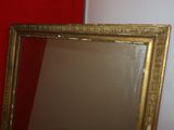 a mirror with a gold frame on a red wall