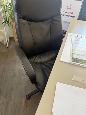 a black office chair sitting next to a desk with papers on it