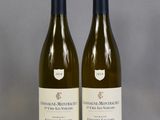 two bottles of white wine sitting on top of a glass table