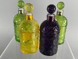three different colored glass bottles sitting on a clear shelf