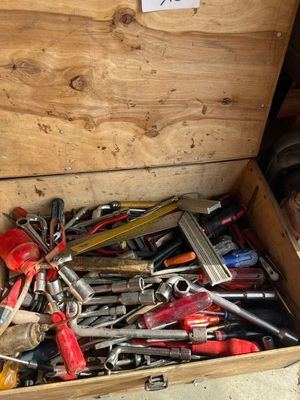 une caisse en bois remplie de divers outils, posée par terre