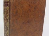 an old brown book sitting on top of a white surface